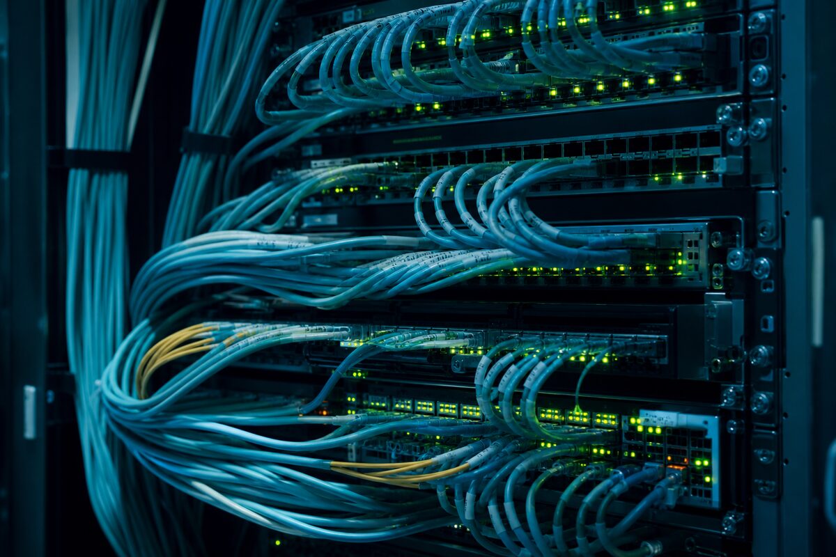 Carrier cabling lit teal inside a data center rack